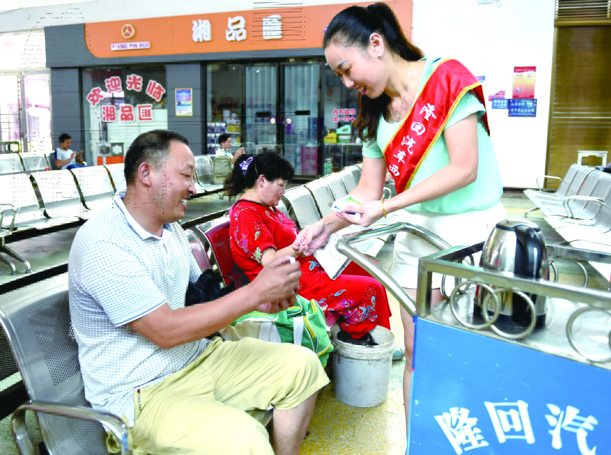 隆回分公司汽車西站工作人員正在為旅客免費贈送藿香正氣水。